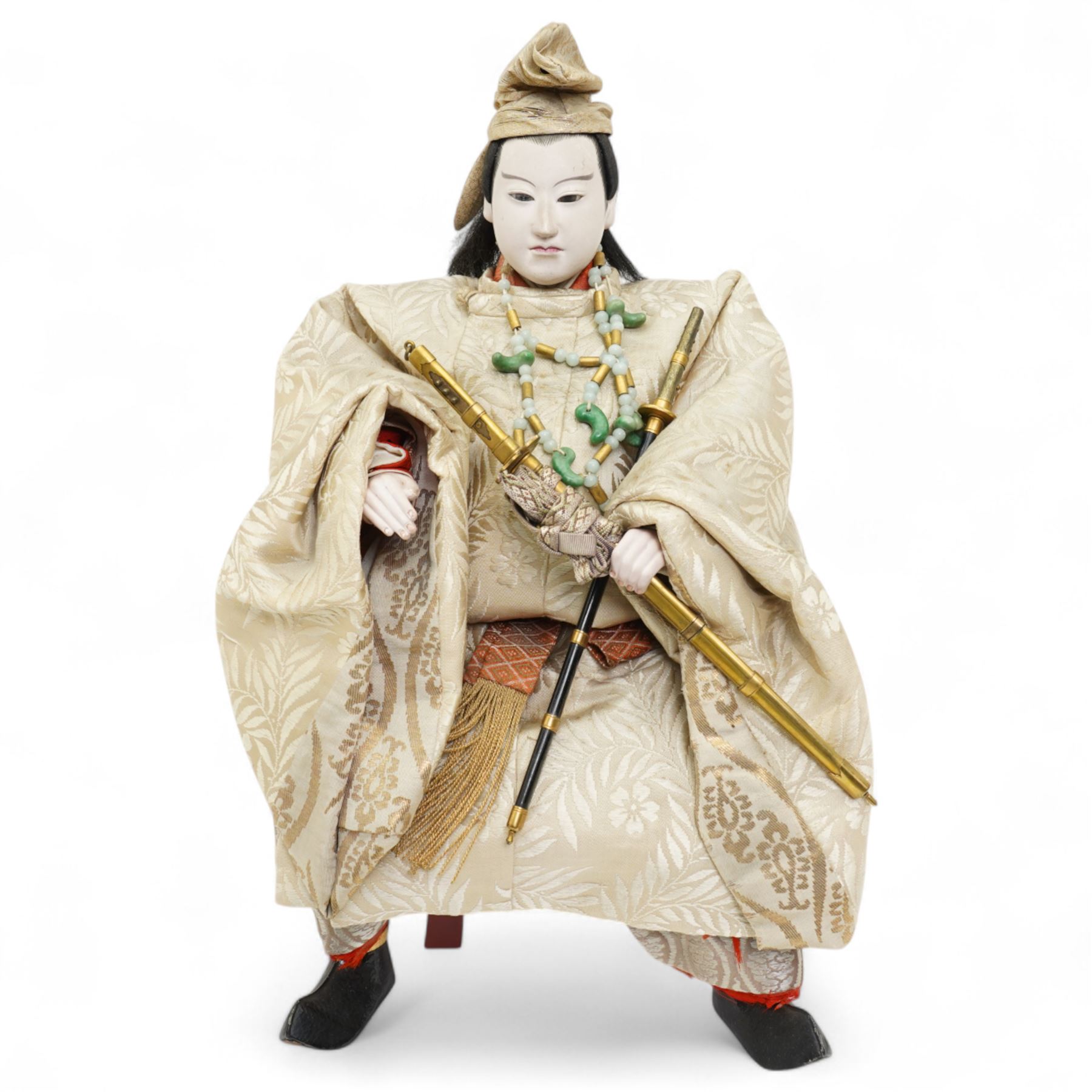Two early 20th century Japanese 'Musha-ningyo' or Warrior Doll figures, costumed with distinctive armour and attributes, the first seated on lacquered red stool the other on a taxidermy rug, seated figure H44cm (2)
