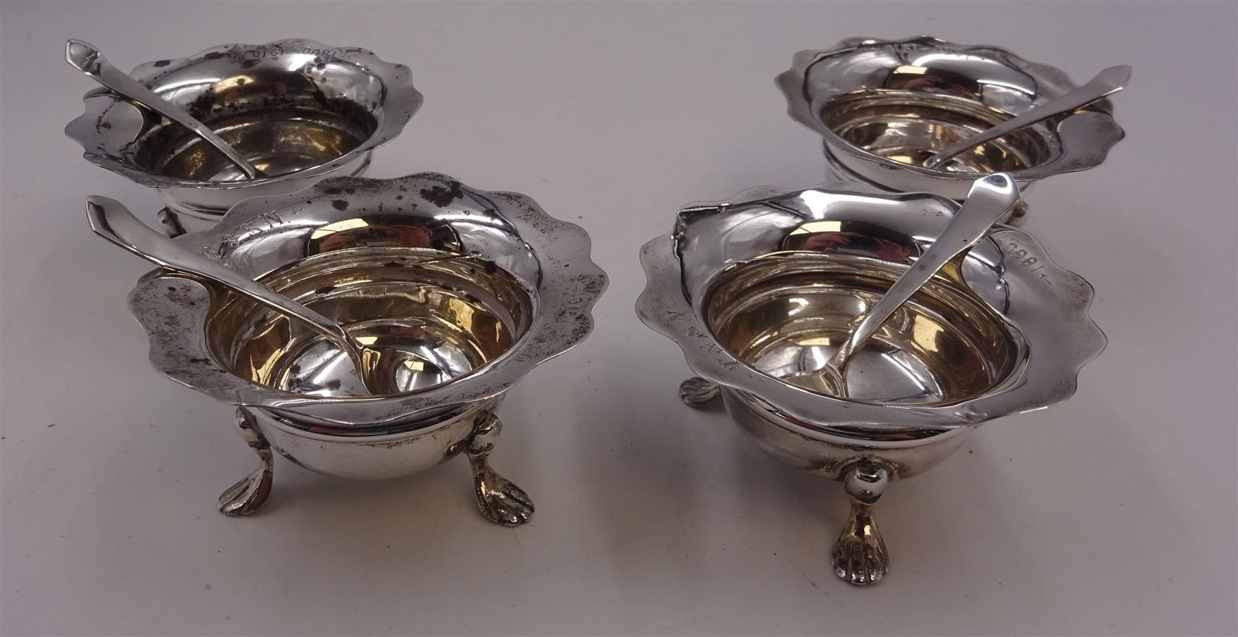 Set of four Edwardian silver open salts, of circular form, each with later personal engraving to scalloped rim and upon three pad feet, together with four matching silver salt spoons, hallmarked James Deakin & Sons, Sheffield 1909, in velvet and silk lined fitted case     