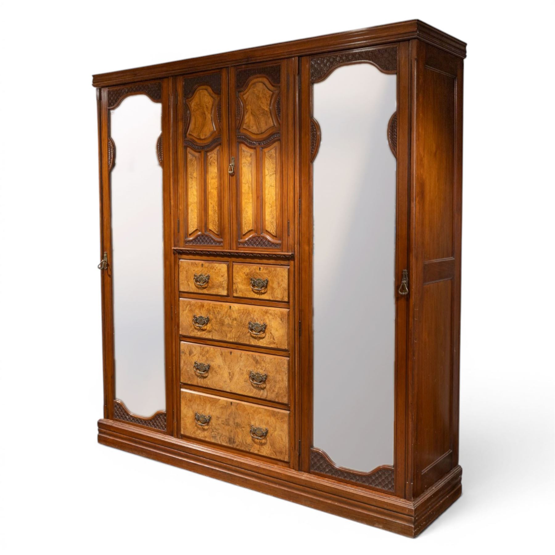 Edwardian figured walnut triple combination wardrobe, moulded cornice above a three part wardrobe, central section with figured walnut panelled doors, above two over three drawers, flanked by mirrored doors enclosing hanging hooks, raised on a plinth