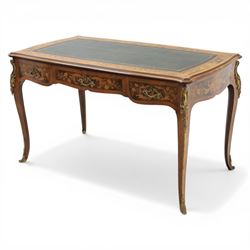 Late 19th century French kingwood and marquetry bureau plat, the serpentine rectangular top with green leather inset writing surface within crossbanded and foliate marquetry border, above a shaped frieze fitted with three drawers with floral marquetry panels and gilt metal handles, upon cabriole supports with applied gilt metal mounts and sabots