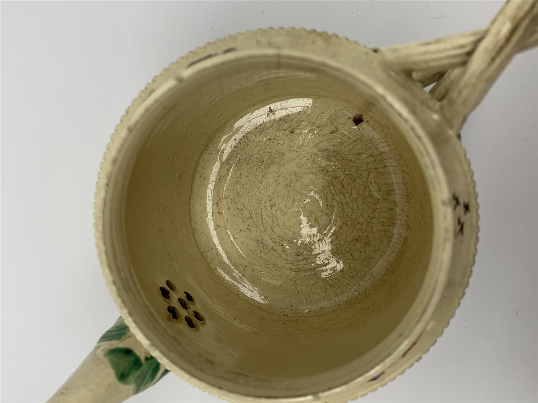 18th century creamware teapot, probably Leeds, with reeded entwined handle and floral finial to the cover, the body with hand painted polychrome decoration of figure to one side, and floral spray to the other, collectors paper label beneath inscribed Leeds Pottery, H11.5cm