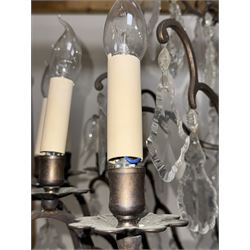 Early 20th century continental cut glass and metal chandelier, with sixteen candle style lights on a single tier of scrolled arms, hung with faceted glass drops and centred by a mould-blown and cut glass baluster stem, suspended from a ceiling rose and chain