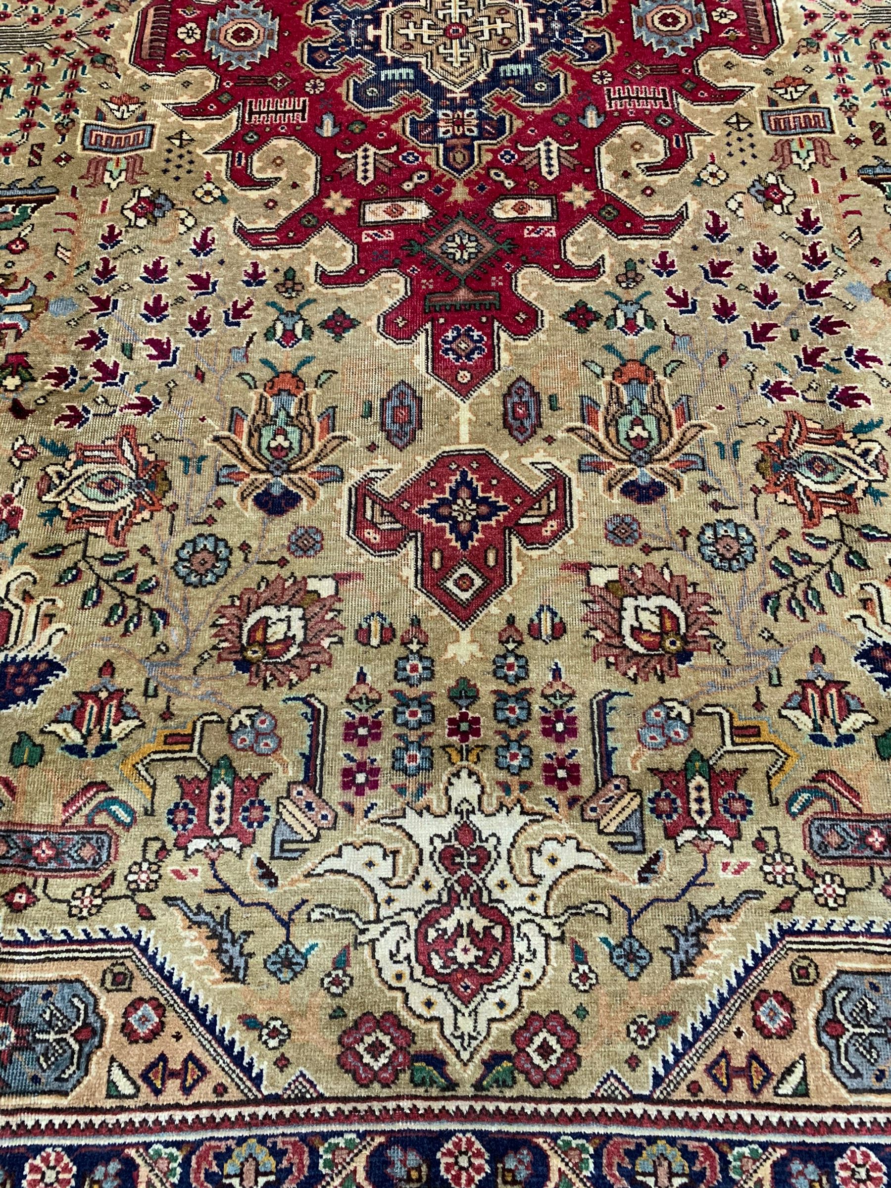 Persian Azarbaijan golden ground carpet, the shaped crimson ground medallion decorated with geometric motifs, the field profusely decorated with stylised plant and flower head motifs, repeating border with guard bands 