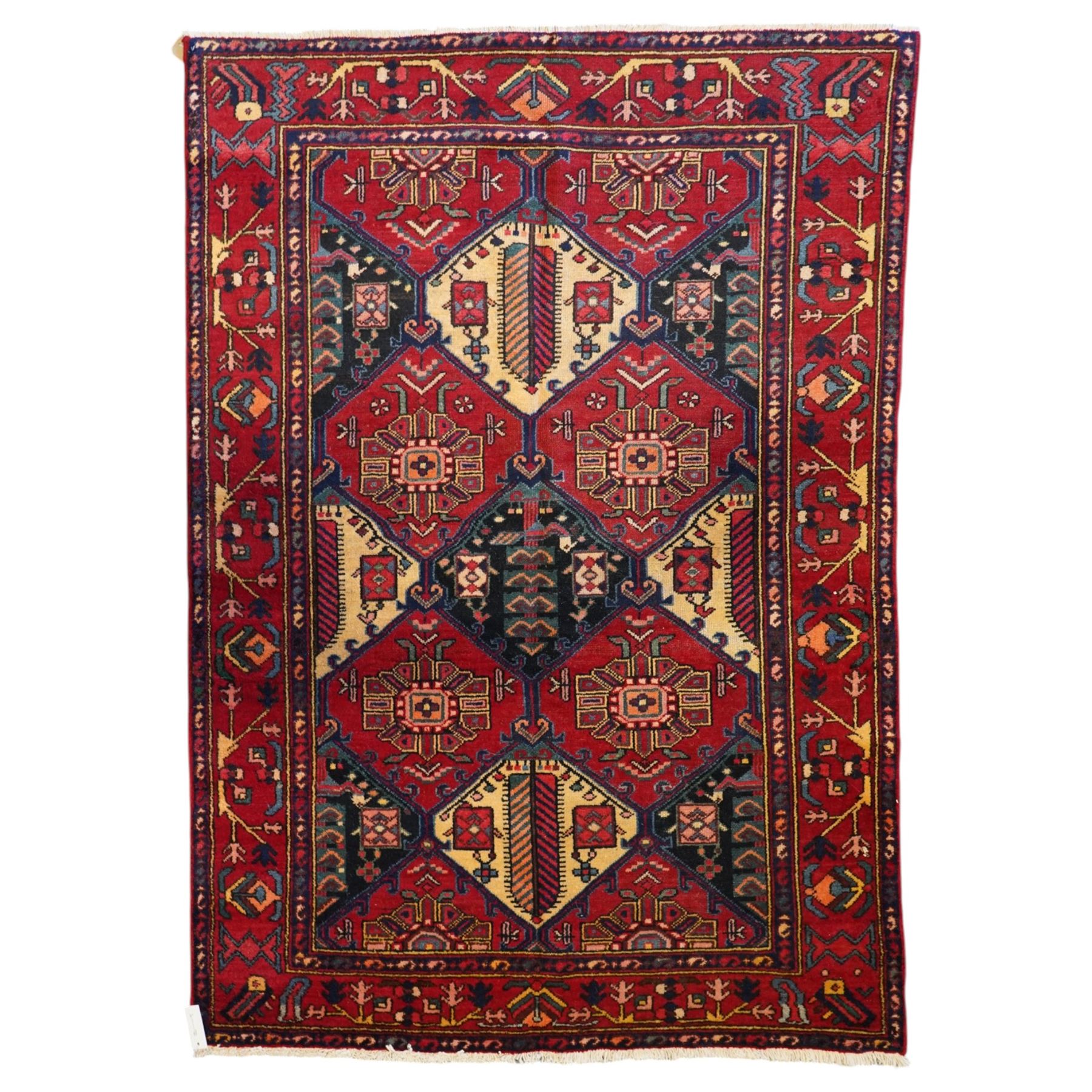 North West Persian Heriz hand-knotted rug, madder red field with an all-over lattice of stepped lozenge medallions enclosing stylized geometric floral motifs and ivory reserve panels, framed by angular vinery and motif borders, main border with with stylized rosettes and geometric devices, flanked by narrow guard stripes,, cotton fringe ends 