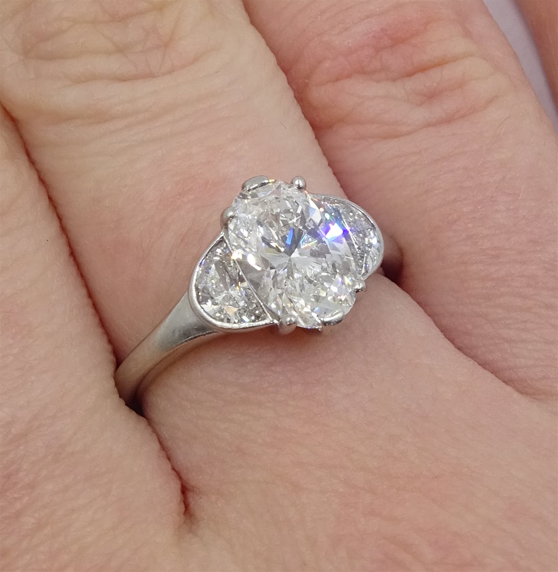 Platinum three stone diamond ring, the oval centre stone of approx 1.80