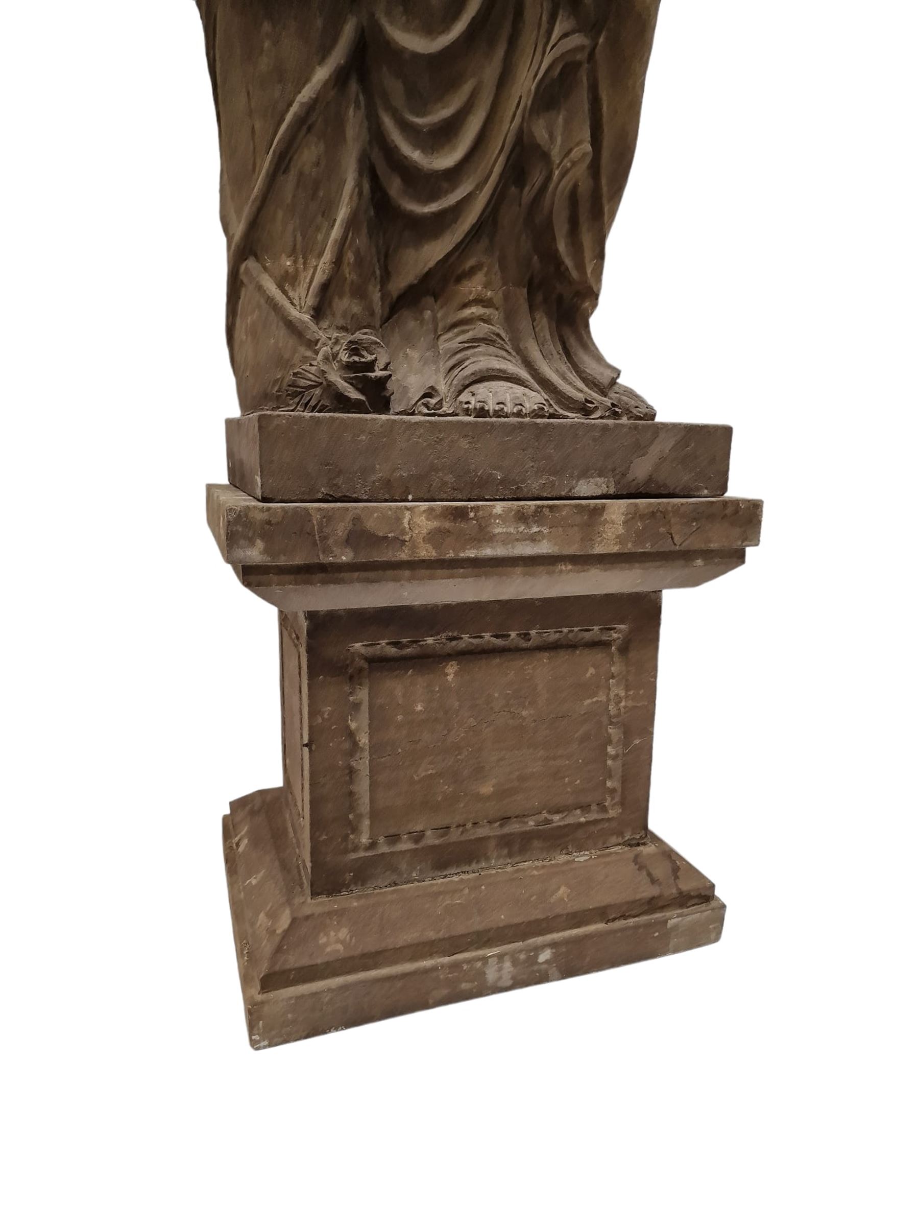 Hand carved stone Neoclassical figure of the Roman goddess Flora, her hair pinned with roses, draped in a toga, holding a basket of flowers in her right hand, raised on a stepped square plinth base 