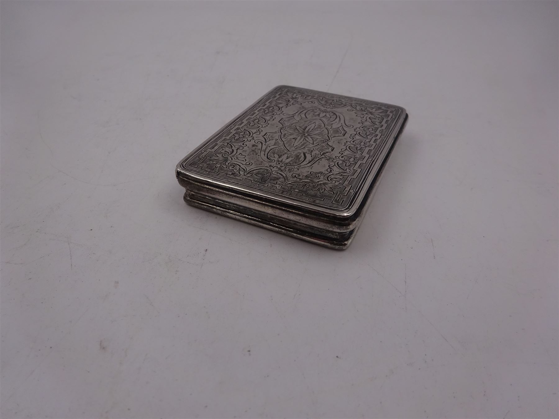 Late Victorian silver snuff box, of rectangular form, engraved with flowers and scrolls, within geometric borders, hallmarked Eustace George Parker, Birmingham 1899, stamped beneath Pearce & Sons Silversmiths, Leeds, W7.6cm