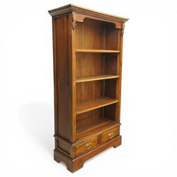 Late 20th century Georgian design hardwood open bookcase, moulded cornice above a shaped frieze, open shelved interior with boarded back, the base fitted with two short drawers with brass swan neck handles, on a shaped plinth