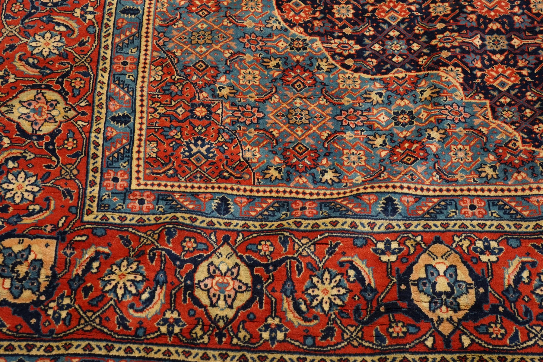 Persian indigo ground Herati rug, the busy field with a central lozenge pole medallion surrounded by repeating Herati motifs, within a shaped spandrel border the crimson guard band decorated with repeating palmette motifs