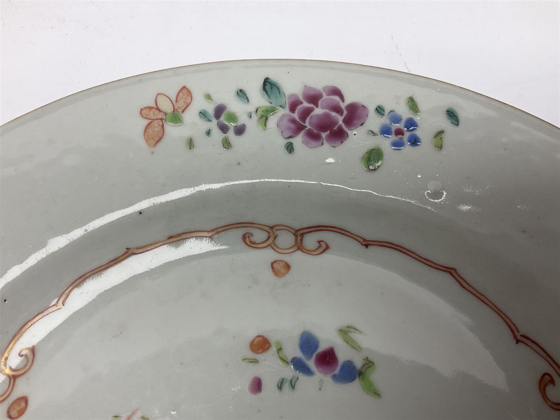 Three 18th century Chinese Famille Rose plates, the first example enamelled with blossoming peonies, rockwork and fence, the other two examples of similar design, decorated with blossoming peonies and sprigs within shaped inner borders, each approximately D23cm