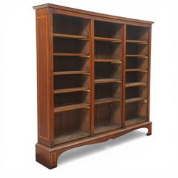 Quality Edwardian inlaid mahogany triple-column open bookcase, projecting cornice over a satinwood banded frieze, fitted with fourteen adjustable shelves with strung facias, the shaped apron on bracket feet