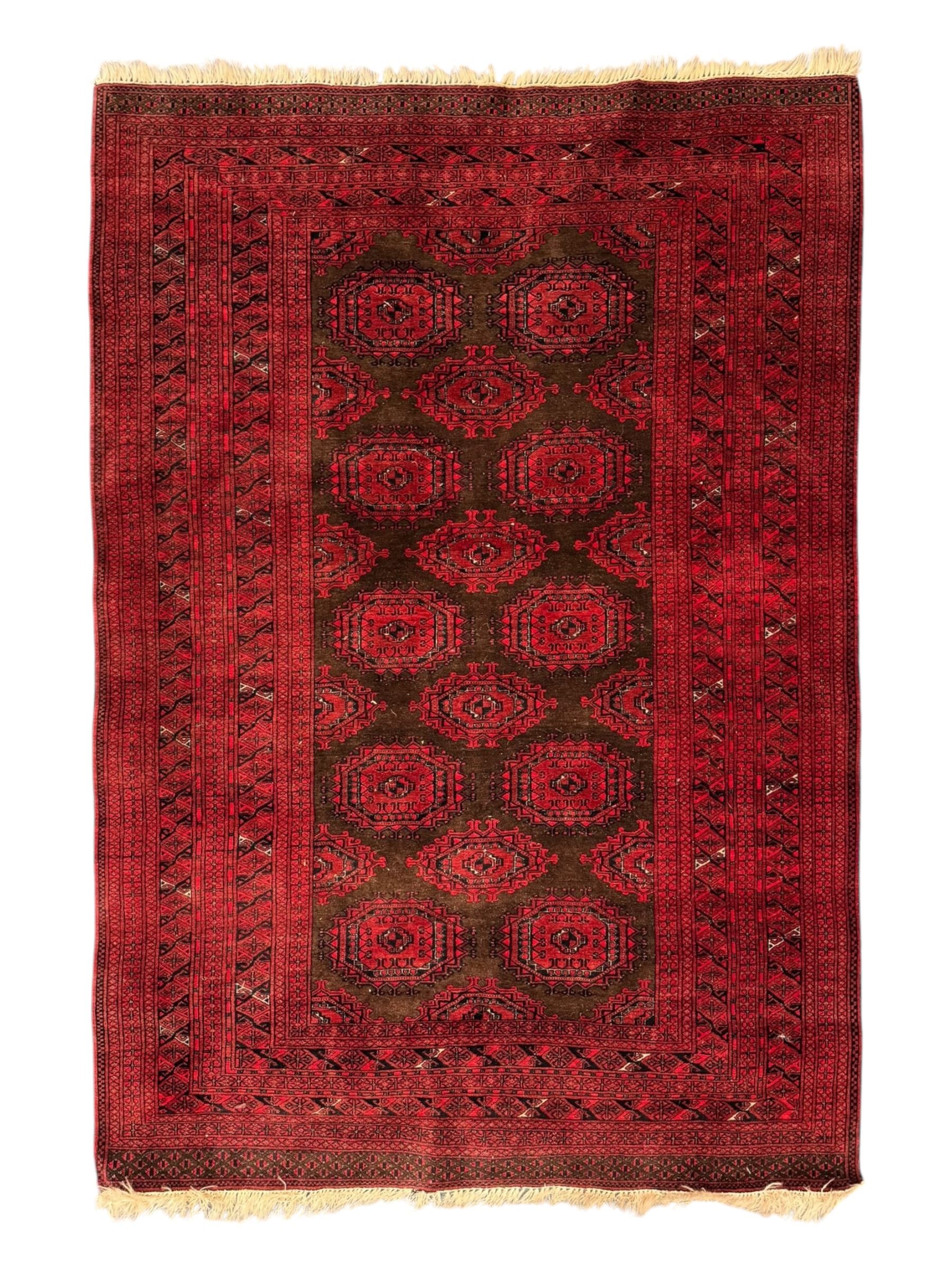 Turkoman red ground wool rug, the field with a repeating pattern of Tekke gul motifs in dark brown and red (195cm x 98cm); Afghan Bokhara red ground wool rug, central field with repeated geometric octagonal gul motifs, surrounded by multiple borders with stylised diamond and triangular patterns (127cm x 181cm)