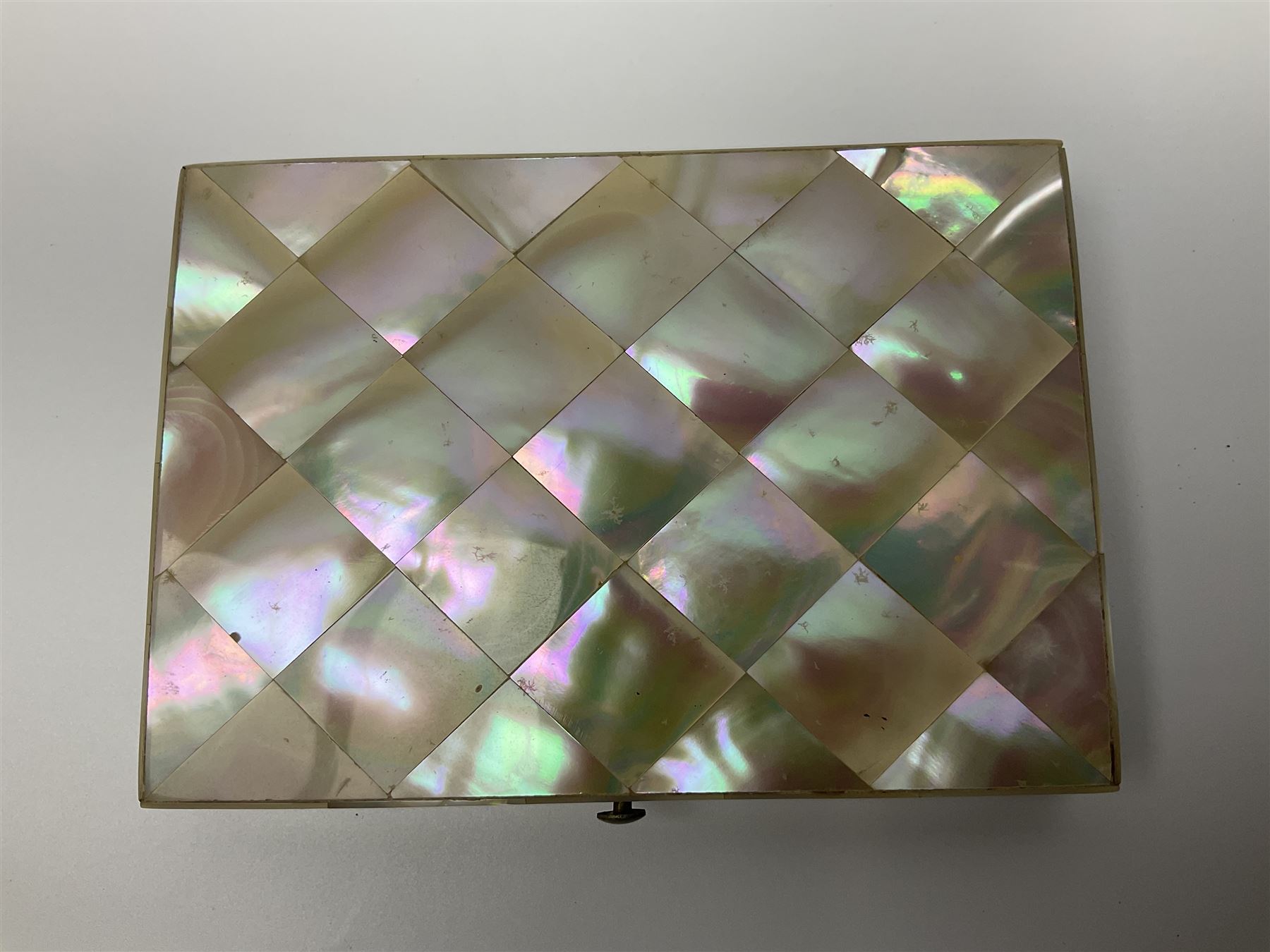 Victorian mother of pearl tea caddy, of rectangular bow-fronted form, the body with floral, bird and geometric engraved mother of pearl panels, white metal shield plaque to the cover inscribed with the initials G.J.A and similar escutcheon, the two division interior with ivory edging and two panelled mother of pearl lids, on four vegetable ivory bun feet L20cm, together with a similar style mother of pearl card case (2) This item has been registered for sale under Section 10 of the APHA Ivory Act