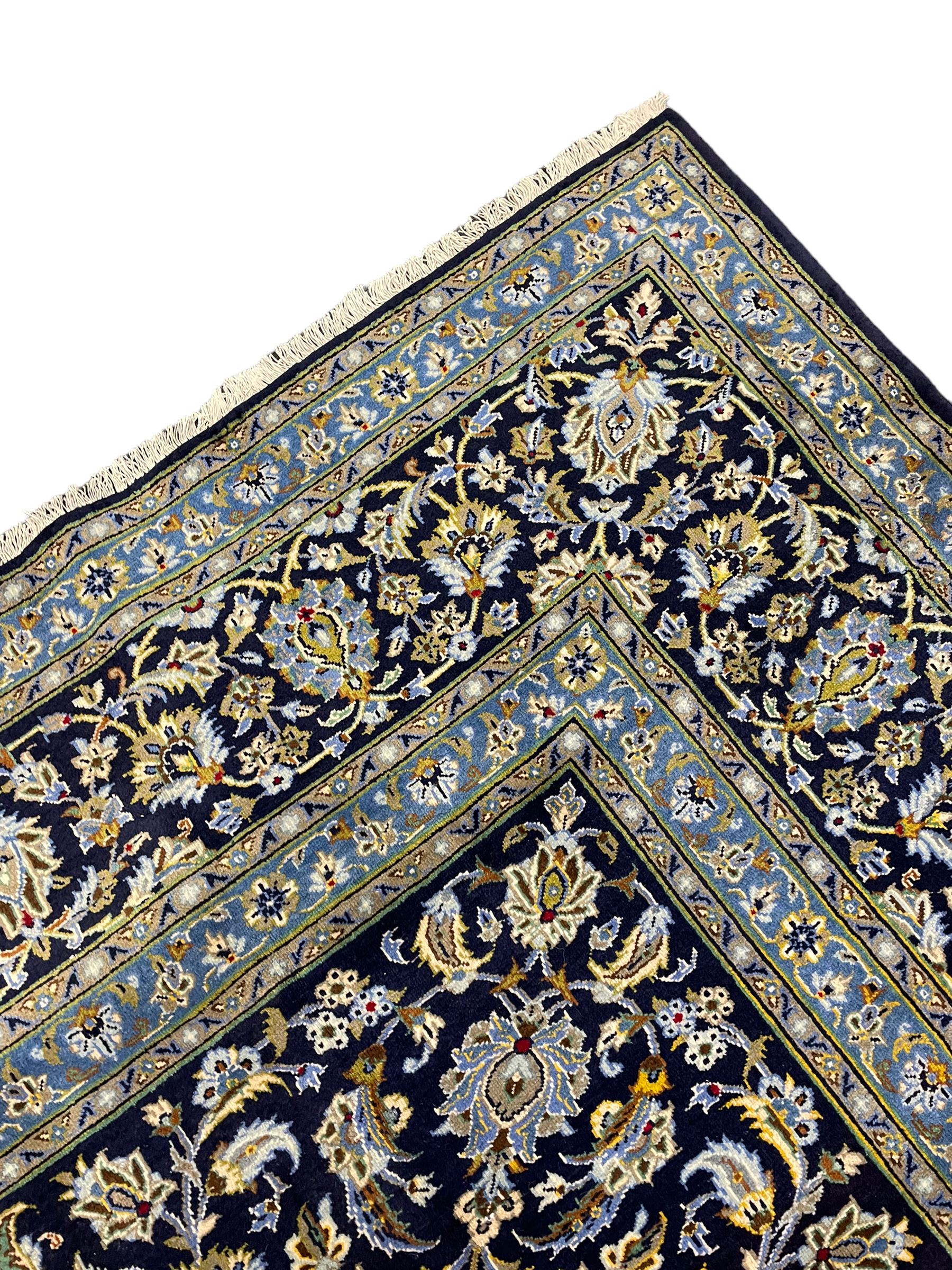 Central Persian Kashan indigo ground carpet, central lighter blue floral medallion surrounded by interlacing leafy branches and stylised plant motifs, the main border decorated with repeating floral motifs and scrolling branches, within guard stripes 
