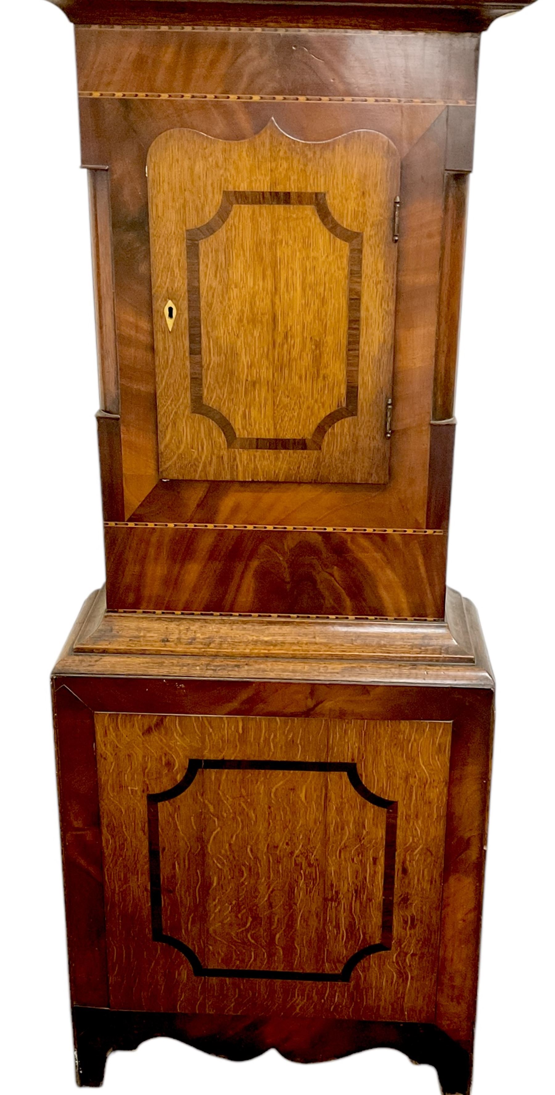 Late 19th century- 8-day mahogany and oak longcase clock, with a swan necked pediment and break-arch hood door beneath flanked by ring turned pilasters, broad trunk with canted corners and a short trunk door with crossbanding and a bone escutcheon, conforming plinth with a shaped base, painted dial with floral spandrels and a country scene to the arch, with Roman numerals, seconds dial and date aperture, dial pinned directly to a rack striking movement, striking the hours on a bell. With weights and pendulum.