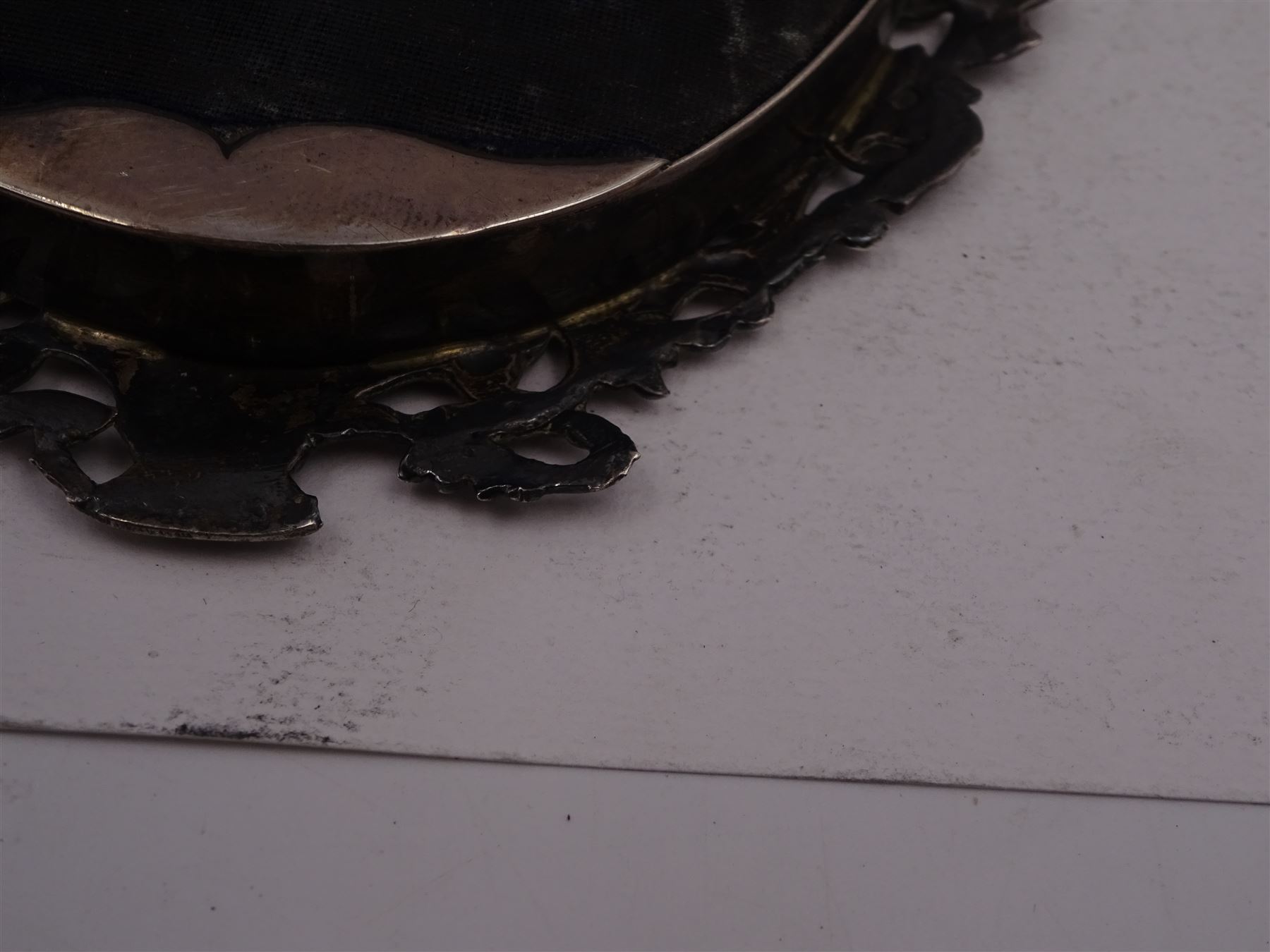 Continental silver miniature dressing table/wall mirror, of oval form with bevelled mirror plate, surrounded by a bead and dart rim, with pierced scrolling floral border with a standing cavalier to either side and the bust of a cavalier to the base, H17.7cm