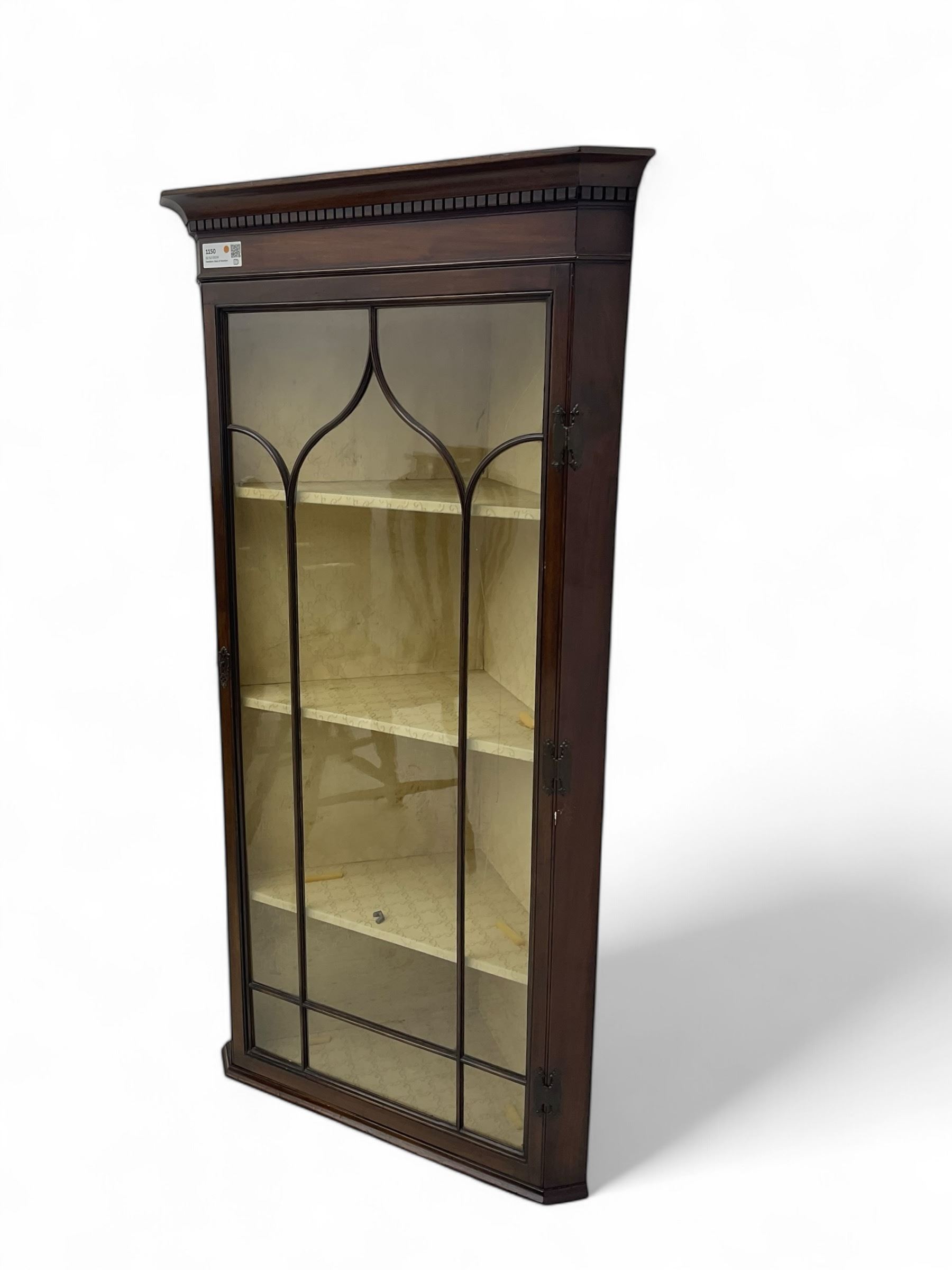 Early 20th century Georgian design mahogany wall-mounted corner display cabinet, projecting cornice with dentil frieze over astragal glazed door enclosing three fabric-lined shelves