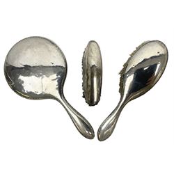 Silver mounted dressing table hand held mirror, together with a matching silver mounted hair brush, and a silver mounted clothes brush, all hallmarked 