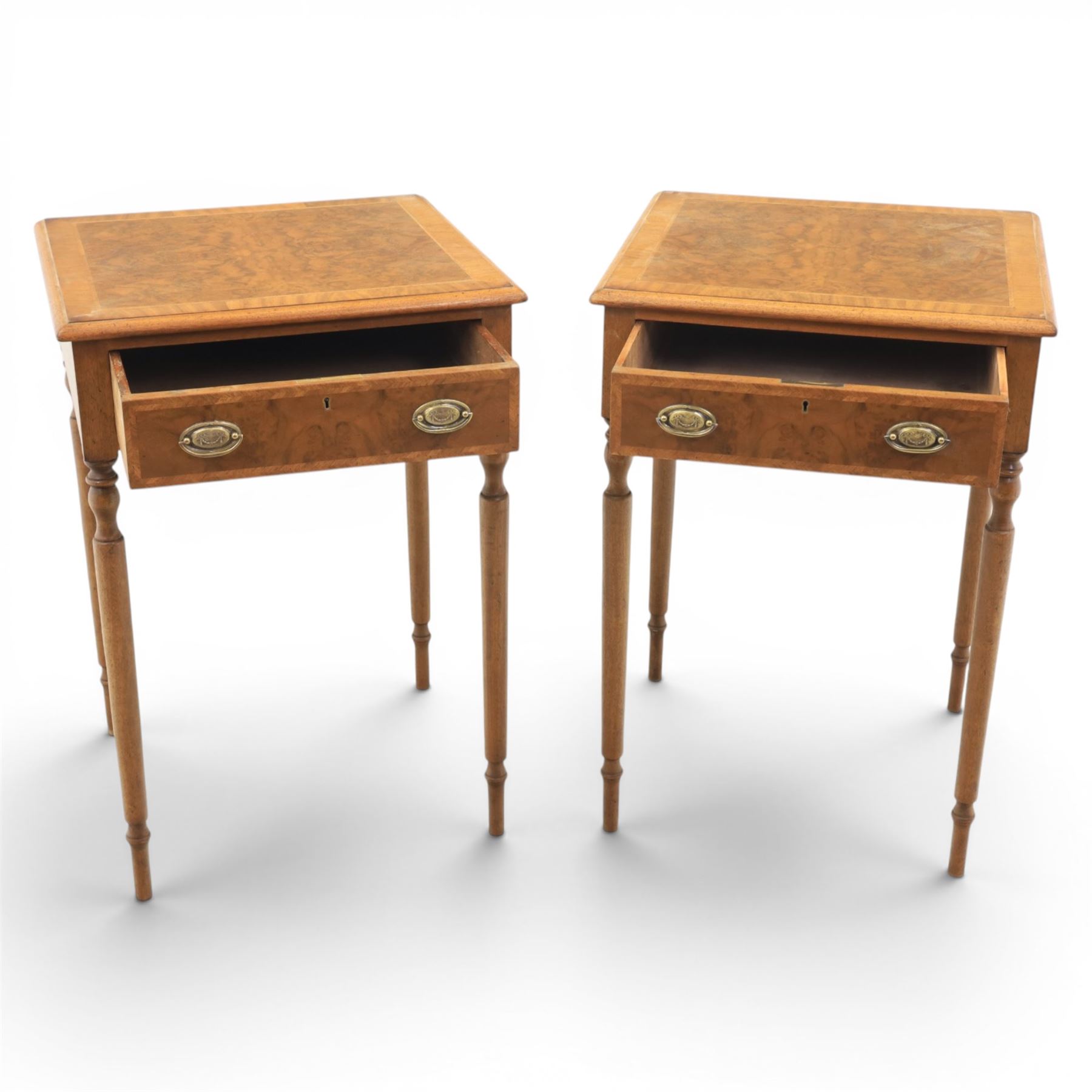 Traditional design pair of walnut lamp tables, figured top with crossbanded edge, above a single frieze drawer with brass oval handles, raised on turned supports