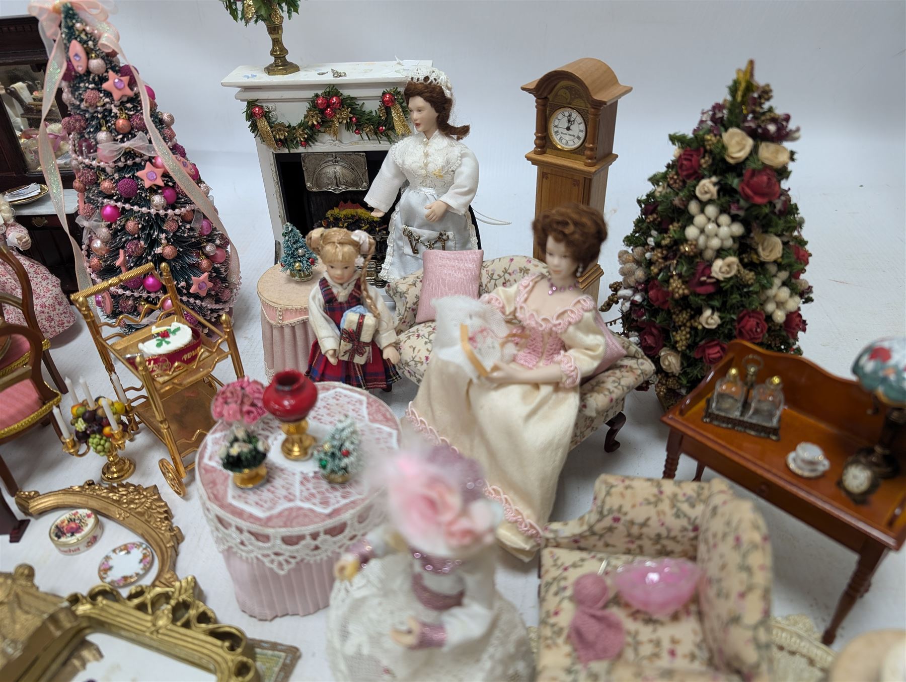 Dolls house living room and ding room furniture, including sofa, chair, long case clock, Christmas trees, fireplace, dresser, chairs, tables, mirrors, seven figures and a collection of predominantly Christmas themed decorations, food, etc