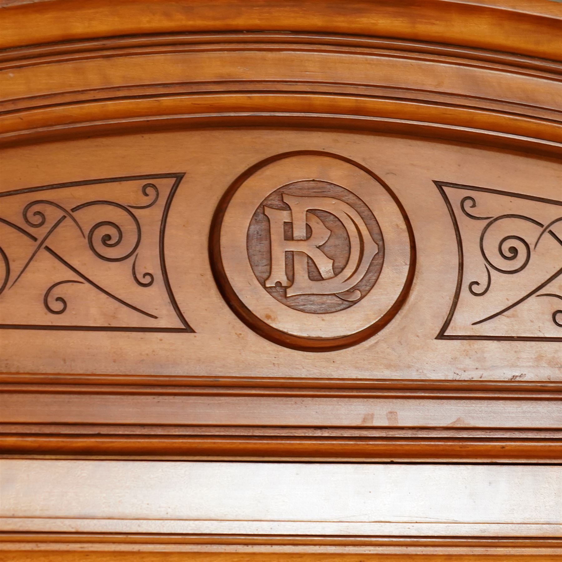 Victorian neoclassical style satinwood triple-section wardrobe, the central mirror section and arched pediment with carved monogram flanked by two panelled crossbanded doors, revealing two drawers and grooves for shelves, the hanging cupboards each with a single drawer, the whole supported on a plinth base