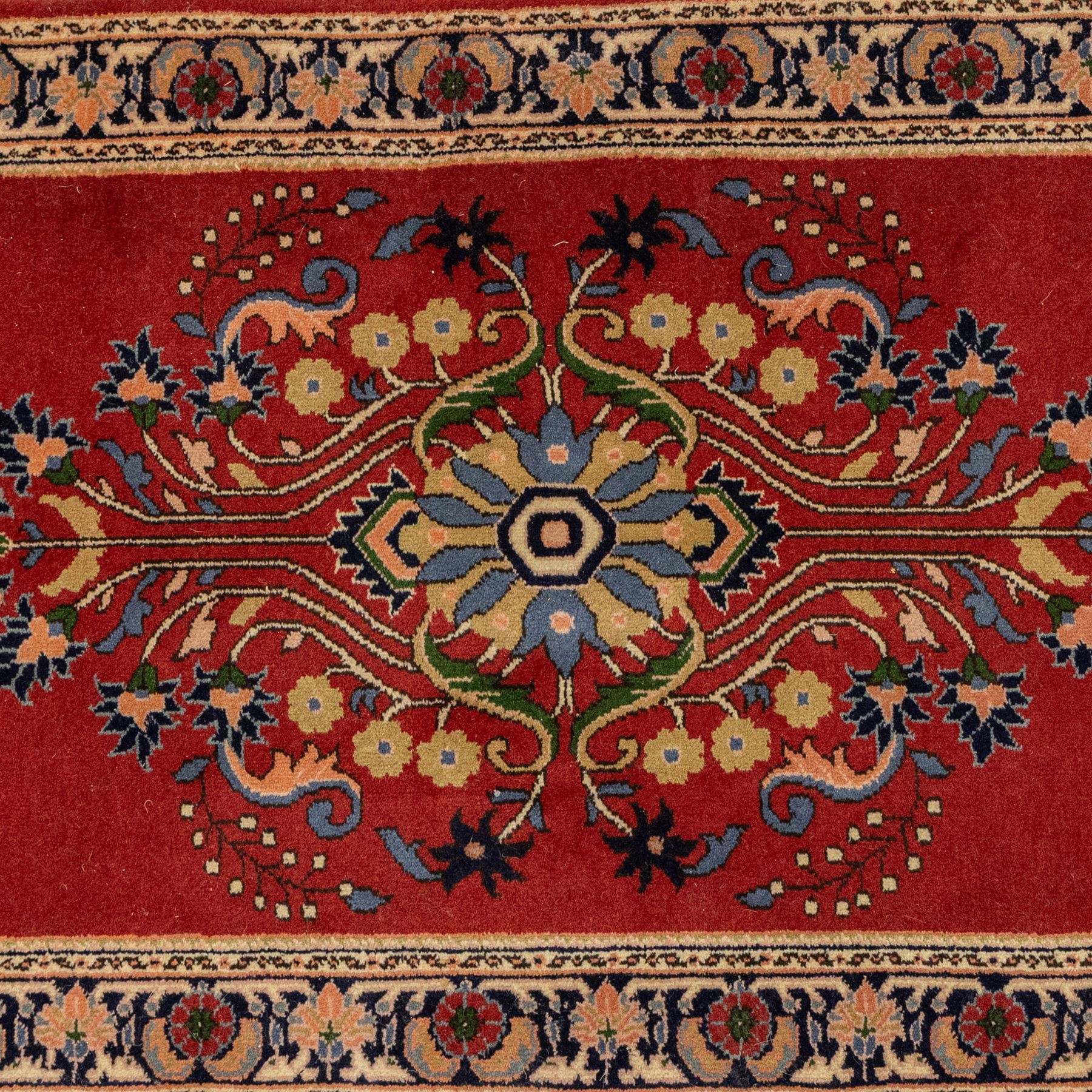 Kashan design wool runner, red field decorated with repeating floral medallions, palmettes and scrolling foliate motifs, enclosed by cream floral border and fringed ends