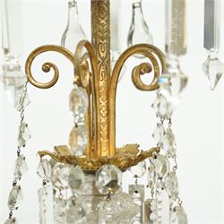 Late Victorian gilt bronze mounted crystal chandelier, ceiling rose above shaped top of trailing swags, glass crystal droplets, beneath rising curled branches and glass beads tapering down to five candle sconces, inside circular bezel fitted with drops and glass twist fluted stem, supported with an internal metal shaft above a rococo style stem holding double branches, and similar styled branches, with twelve branches fitted with candle holders and drip trays with crystal drops and cut crystal spears, the underside festooned with crystal glass swags and a bulbous fluted glass terminal and shaped finial with crystal glass swags attached to the branches, the base with pear shaped droplet graduating to the centre, wired for electricity 