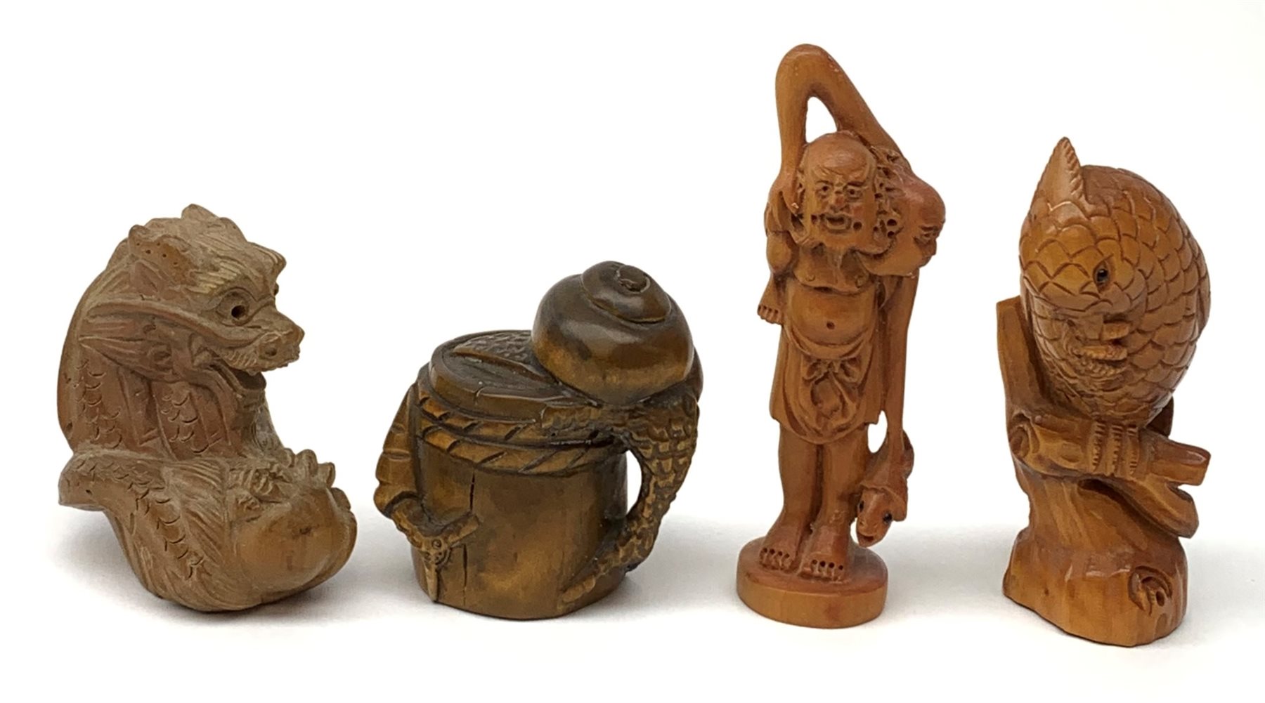 Four carved wooden Japanese netsukes, modelled as a dragon, two snails upon a log, a bird perched upon a branch, and a fisherman with figure upon his back, each signed beneath. (4). 
