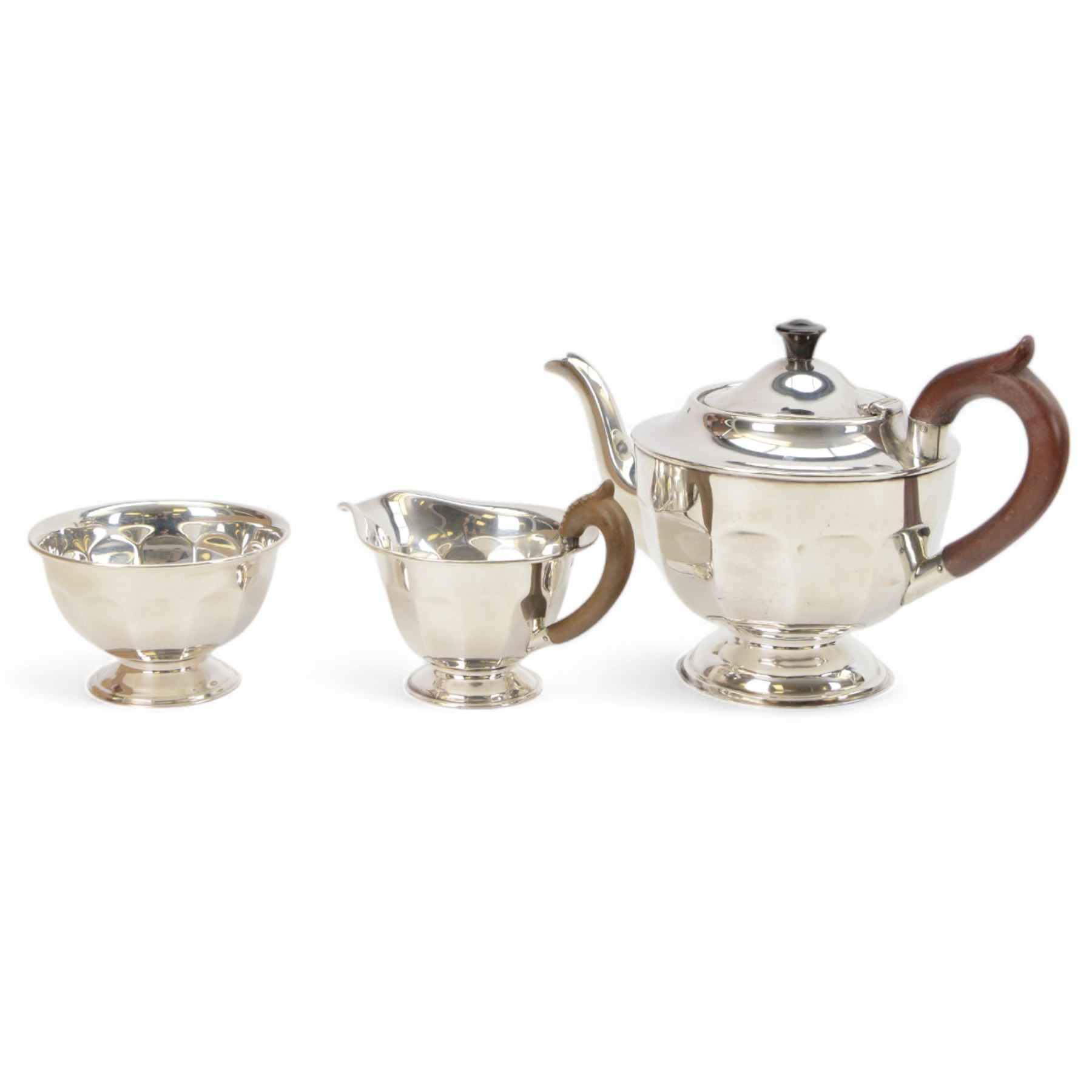 1930s silver three piece tea service, comprising teapot, open sucrier and milk jug, each of circular part fluted form, the jug and teapot with Bakelite type handles, hallmarked Viner's Ltd,  Sheffield 1935