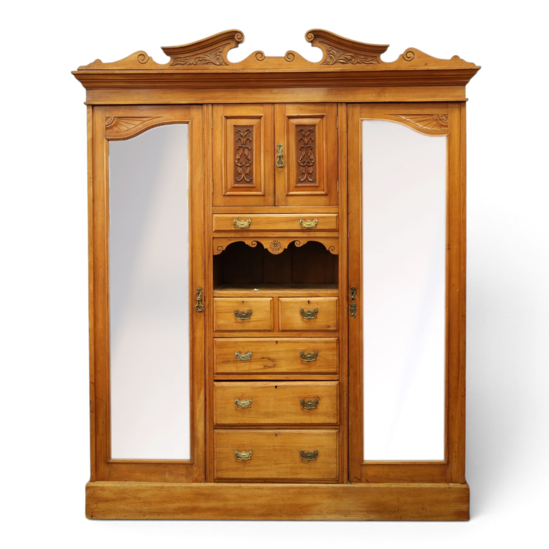 Edwardian walnut triple combination wardrobe, projecting pediment with pierced foliate scroll cresting above a central cupboard flanked by bevelled mirrored doors, over open recess with mirrored back, above two short and three long drawers with brass handles, interior fitted with hanging rails and shelf, raised on plinth base
