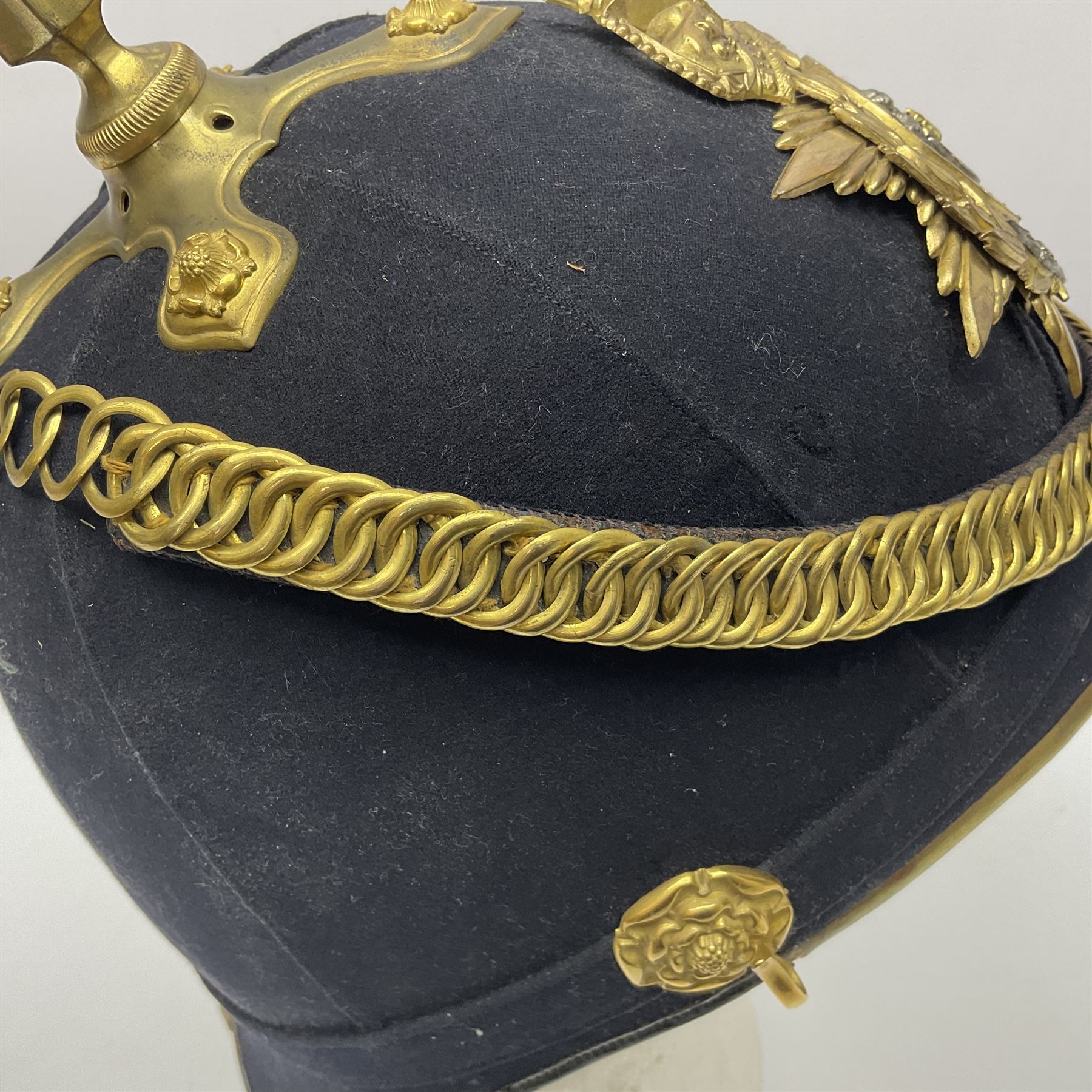 Post-1902 Welsh Regiment Officer's Home Service Blue Cloth Helmet with gilt metal King's crown helmet plate to the front, a removable spike to the top on a shaped cruciform base with rosette fittings, rosette side bosses, brass trim to the front peak, and leather and velvet backed chin scales, with sweat band, the interior with the remains of a makers label at the address 1,3 & 5 Lexington Street, Golden ? London W (presumably Hobson & Sons)