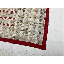 19th century patchwork quilt, hand stitched from hexagons of various materials predominantly in neutral tones including printed floral examples, with alternating red and white striped centre, bordered in red, 190 x 238 cm