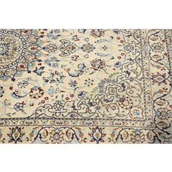 Central Persian Nain hand-knotted silk and wool rug, ivory field with a cusped medallion  issuing radiating pendants, with an all-over design of scrolling arabesques, palmettes and floral sprays, framed main border of meandering vinery and stylized palmettes, flanked by narrow guard stripes, cotton fringe ends  