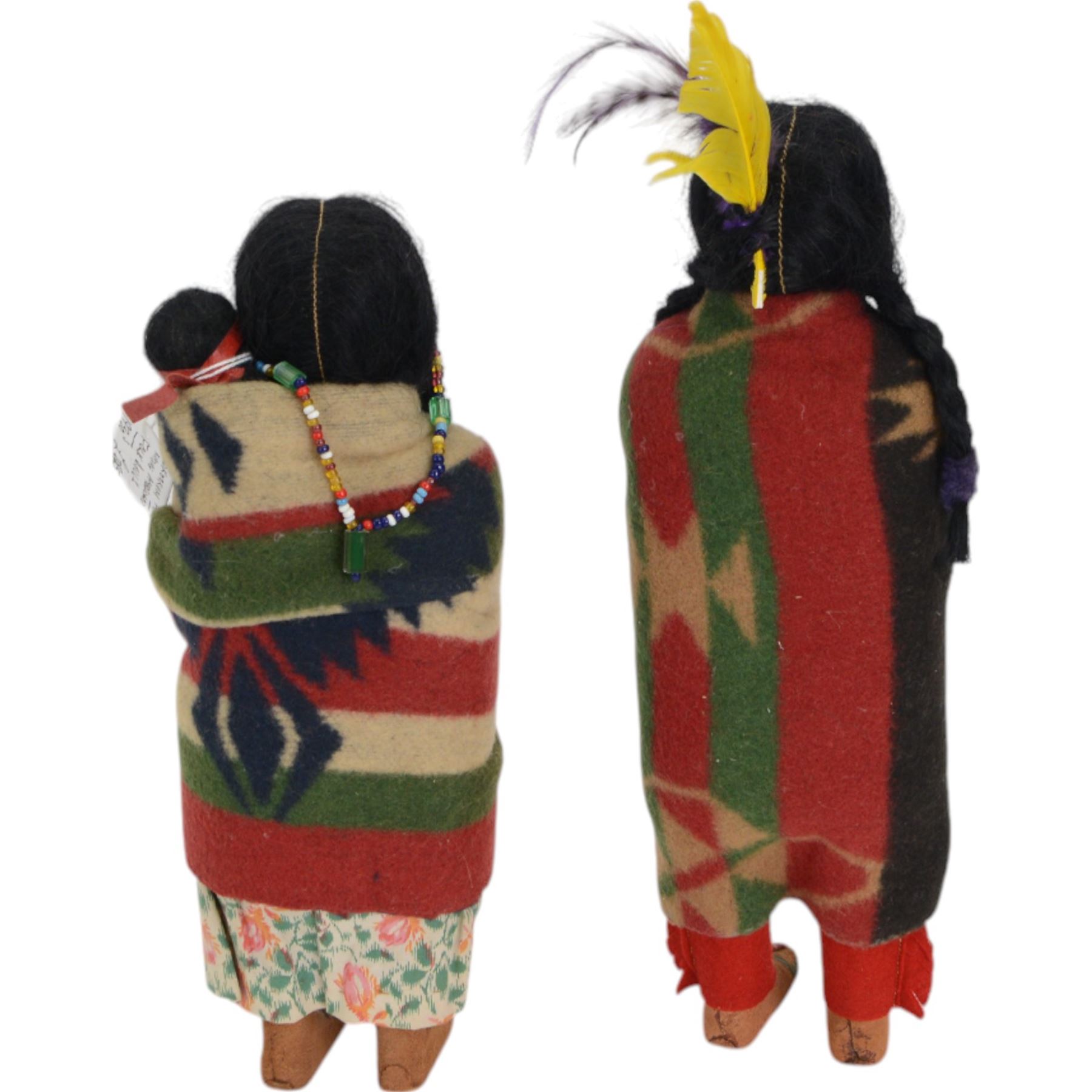 Two Skookum Native American Indian dolls with foot label, with painted composition heads, side glancing eyes, black hair wig, stuffed rigid body, original clothes, the male with feather headdress, the female with baby on back, H32cm