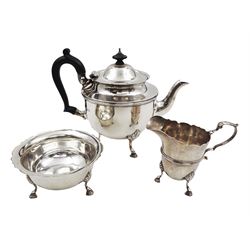 1920s three piece silver tea service, comprising teapot, with ebonised wooden handle and finial, milk jug and open sucrier, all of circular form, with shaped rims, and upon three hoof feet, hallmarked Wakely & Wheeler, London 1922, teapot H19cm