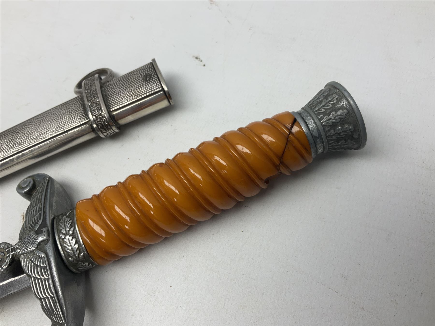 Late WW2 German Army Officers dress dagger, with unmarked 25cm double edged steel blade, orange celluloid grip, pommel and ferrule with oakleaves relief and cross guard with eagle; in original beaded scabbard with two hanging rings L39.5cm overall