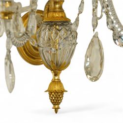 Pair of George III ormolu and cut-glass wall-lights, each with a tall central urn-shaped finial above a series of faceted glass spires and scrolled branches, the ormolu-mounted nozzles and drip pans hung with festoons of cut-glass drops and pear-shaped pendants, the lower section centred by a pineapple finial, wired for electricity