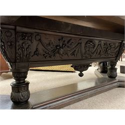 Large 19th century carved oak library table, the rectangular top with lunette carved edge over cartouche panelled and carved  scroll frieze, the central tapering rectangular support relief carved with masks and garlands, on four carved seated lion supports at each corner, on flat angular stretcher with recessed castors stamped ‘Bartholomew & Fletcher, London’