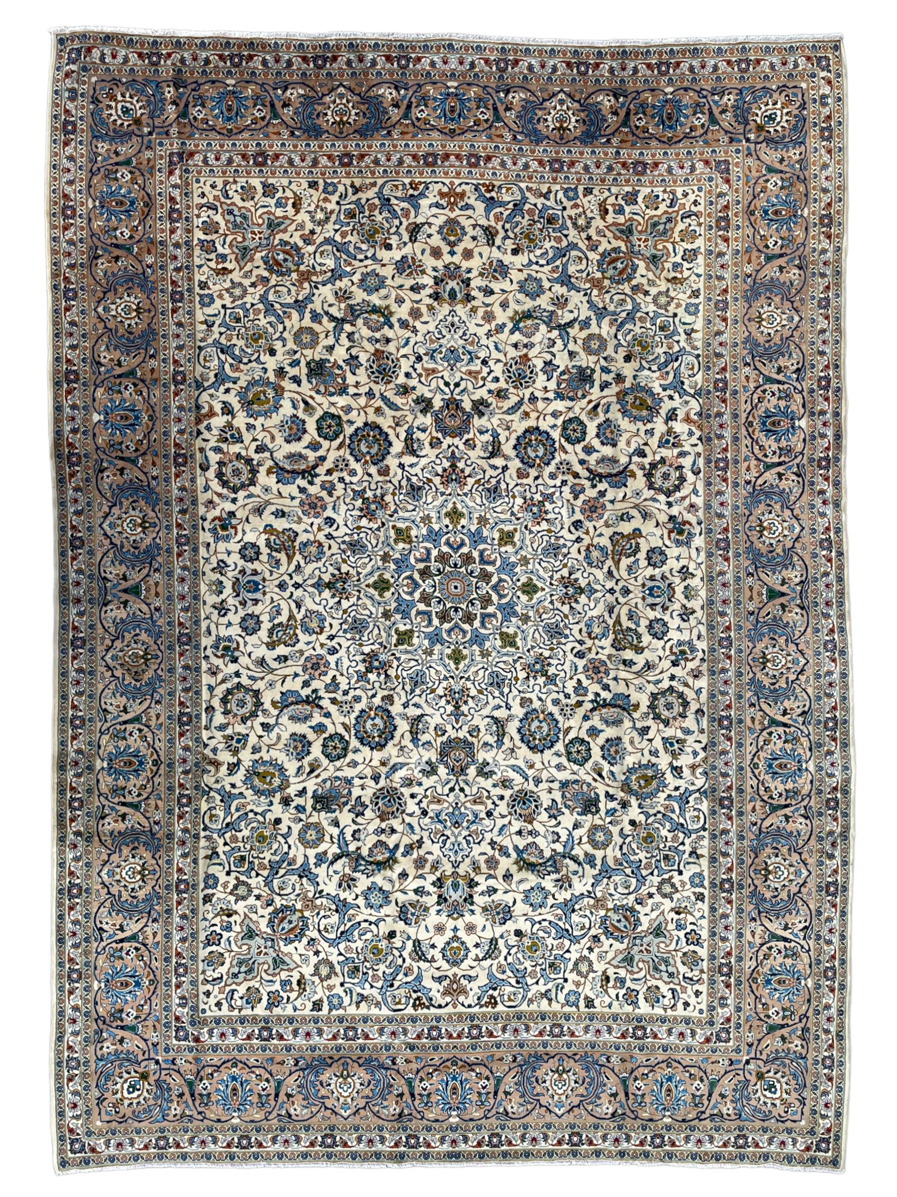 Persian Kashan ivory ground carpet, the interlaced foliate medallion surrounded by trailing plant motifs interlaced with scrolls, the guarded border with repeating stylised flower heads