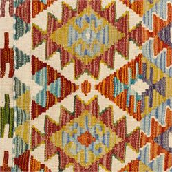 Chobi flatweave kilim runner with a repeating stepped diamond medallion design in live green, rust, teal, purple, and ivory, framed by chevron and geometric borders