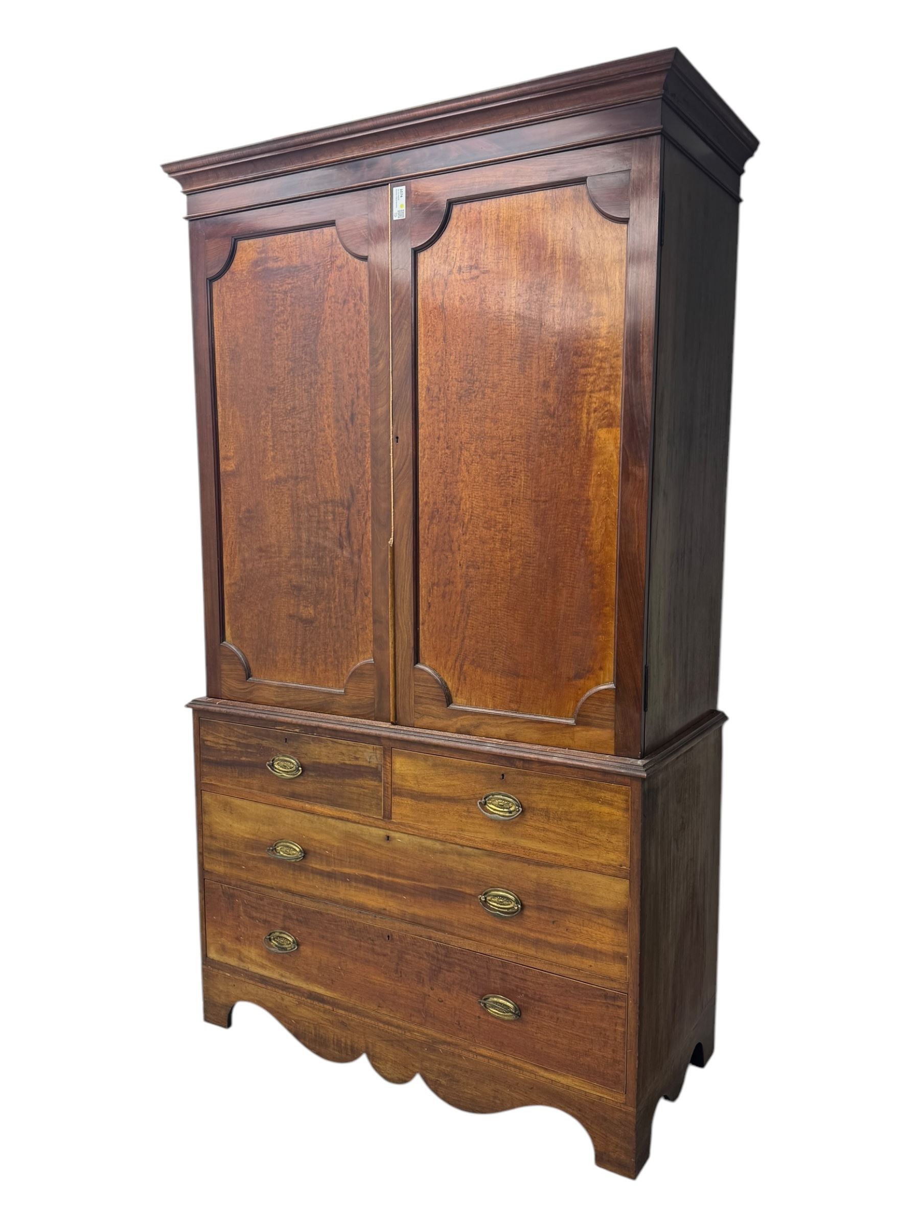George III mahogany linen press cupboard, projecting moulded cornice over two panelled doors, the interior fitted with two slides and shelf, two short and two long drawers below, shaped apron over bracket feet 