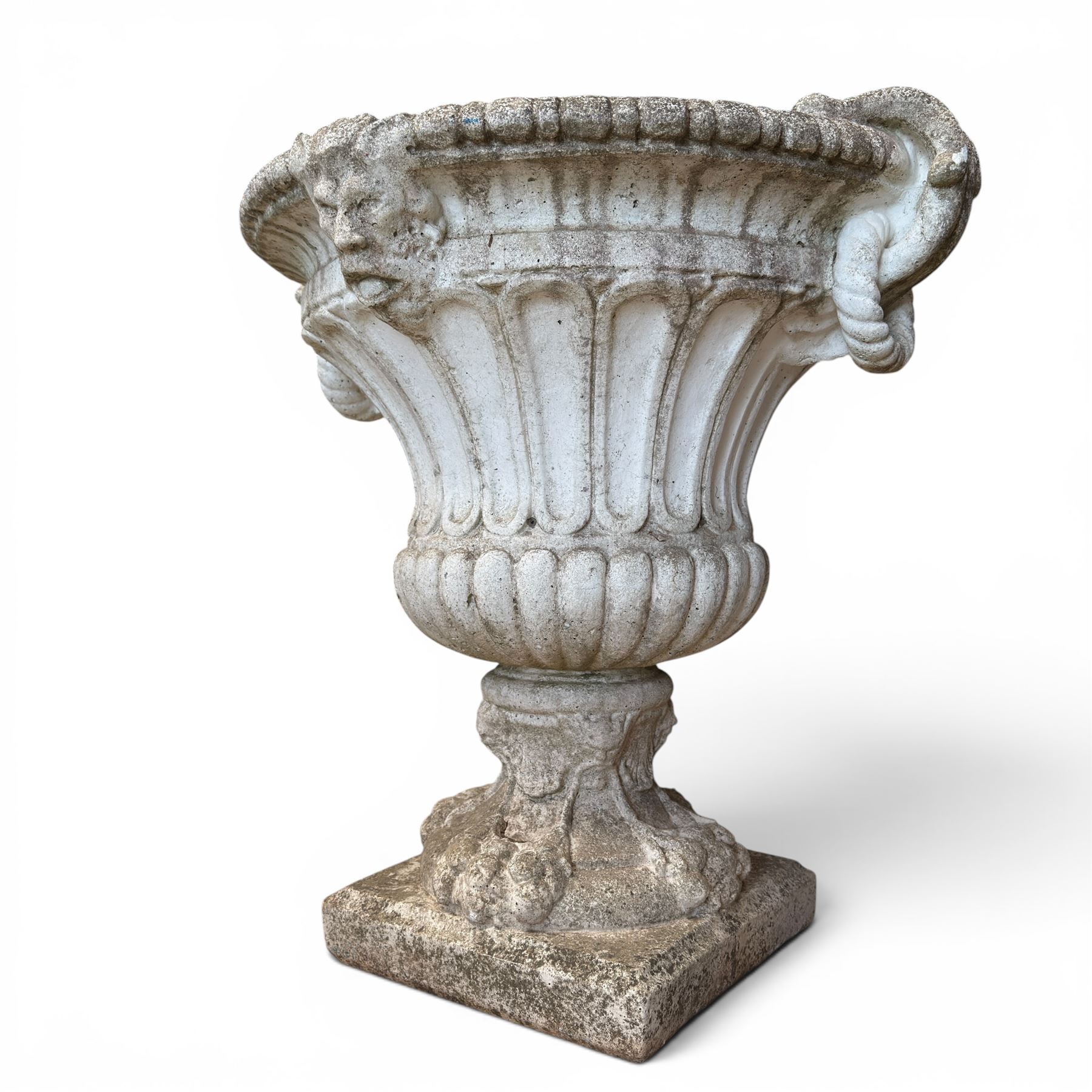 Pair of Neoclassical design cast stone garden urns, each of campana form with fluted body and gadrooned underbelly, decorated with faun/satyr opposing masks and ropetwist handles, with floral and mask design to the socles, raised on square bases, finished in weathered white patina