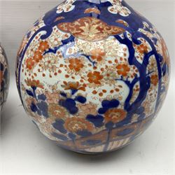 Pair of large 19th century Japanese Imari porcelain bottle vases, painted with shaped reserves of peonies, chrysanthemums and prunus blossom, each H46cm