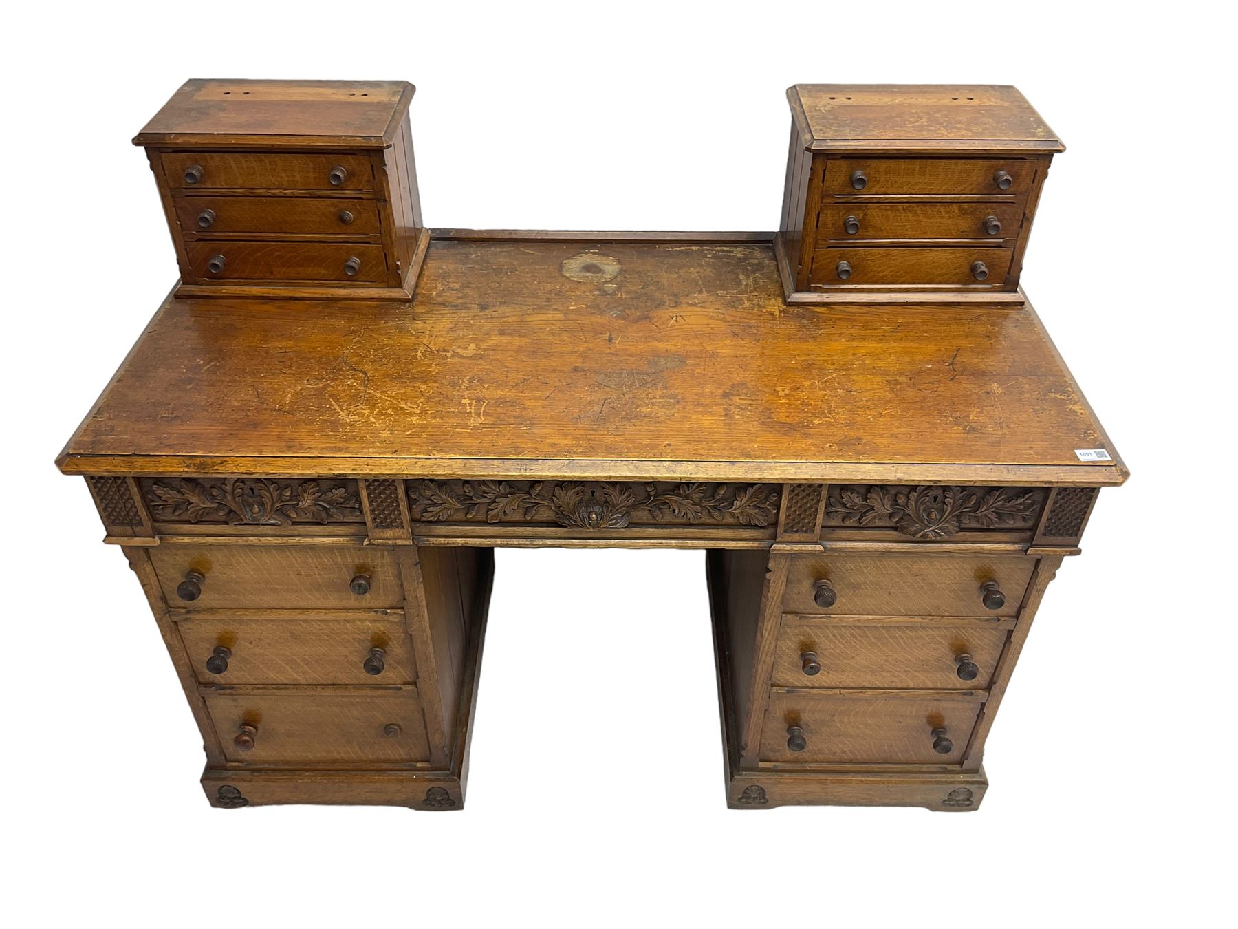 Late 19th century heavily carved oak twin pedestal desk, rectangular top with two raised trinket or correspondence structures each with three drawers, rectangular top over three frieze drawers carved with acorn and oak leaf decoration, each pedestal with three drawers with acorn husk shaped handles