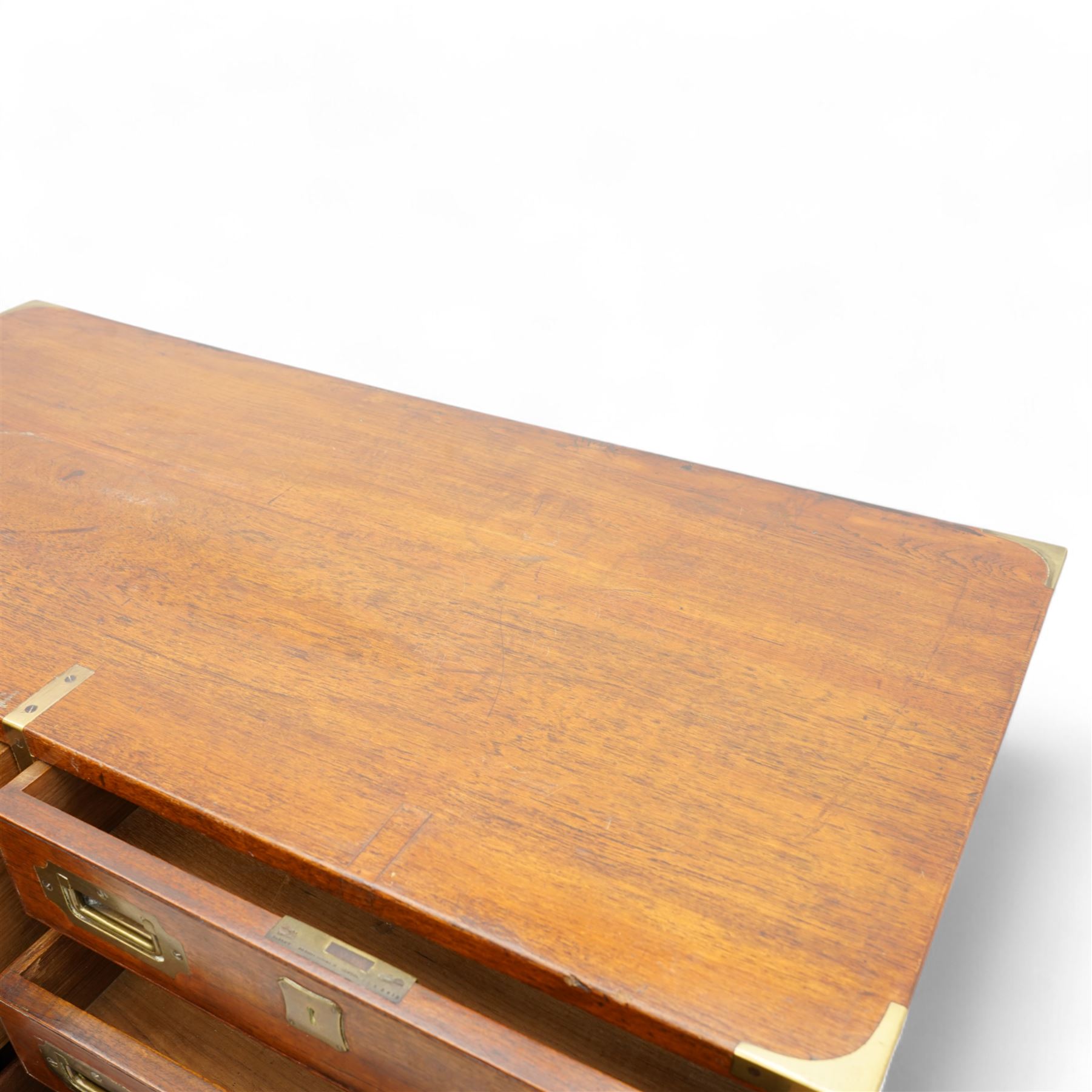 Early 19th century and later teak military campaign chest, mounted and bound with brass strapping and corner brackets, fitted with one deep, two shallow and three long drawers, each with recessed brass handles and shaped escutcheons, on turned feet 