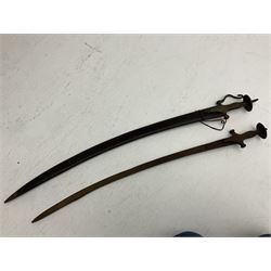Late 19th/early 20th century Indian Tulwar sword with 81cm plain curving steel blade and iron hilt with extended langets, knucklebow and spiked pommel; in leather covered scabbard L100cm overall; and another Tulwar lacking scabbard in almost relic condition (2)