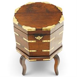 Late 18th century Anglo-Indian padouk and brass-bound octagonal cellarette or wine cooler, the hinged lid enclosing a vacant interior, the panelled body with applied brass strapwork, pierced escutcheon and side carrying handles, raised on a separate stand terminating to four fluted and reeded cabriole supports