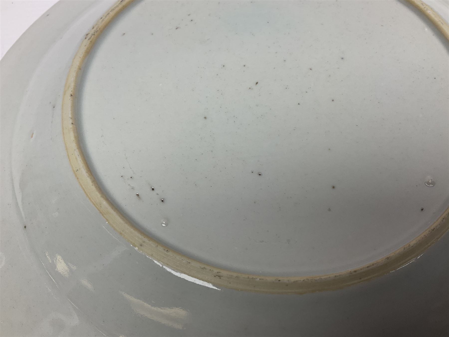 Three 18th century Chinese Famille Rose plates, the first example enamelled with blossoming peonies, rockwork and fence, the other two examples of similar design, decorated with blossoming peonies and sprigs within shaped inner borders, each approximately D23cm