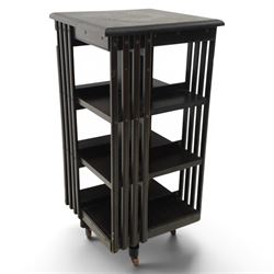 20th century ebonised revolving bookcase, square top with chamfered edges, over a three ti...