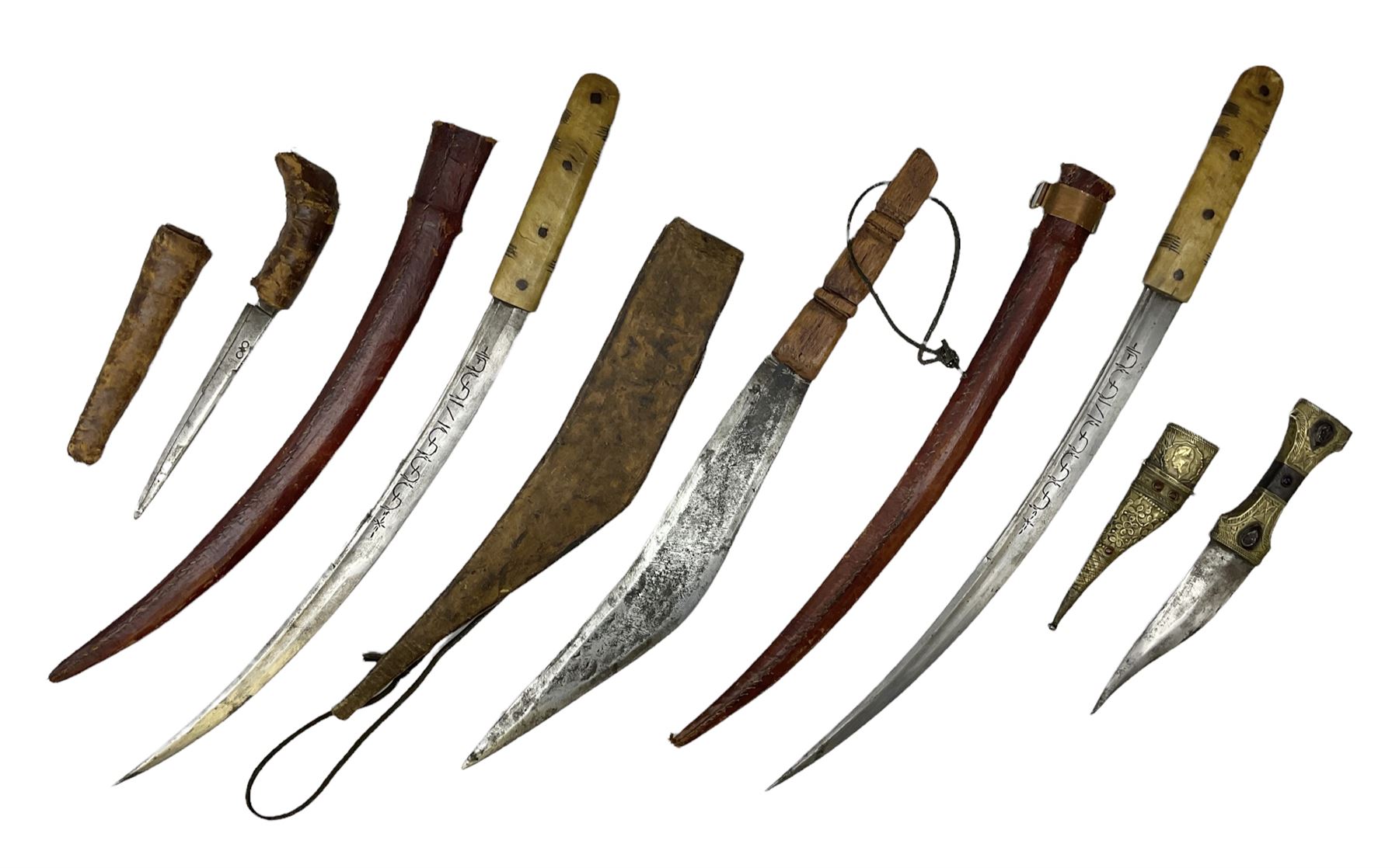 Near pair of African Moroccan Berber tribal Shula daggers each with engraved 39cm curving fullered steel blade, carved and inlaid horn grip and leather covered scabbard L57cm overall; kindjal style dagger with brass covered and jewelled grip and scabbard; another Eastern dagger with leather covered grip and scabbard; and a large Eastern knife with animal hide scabbard (5)